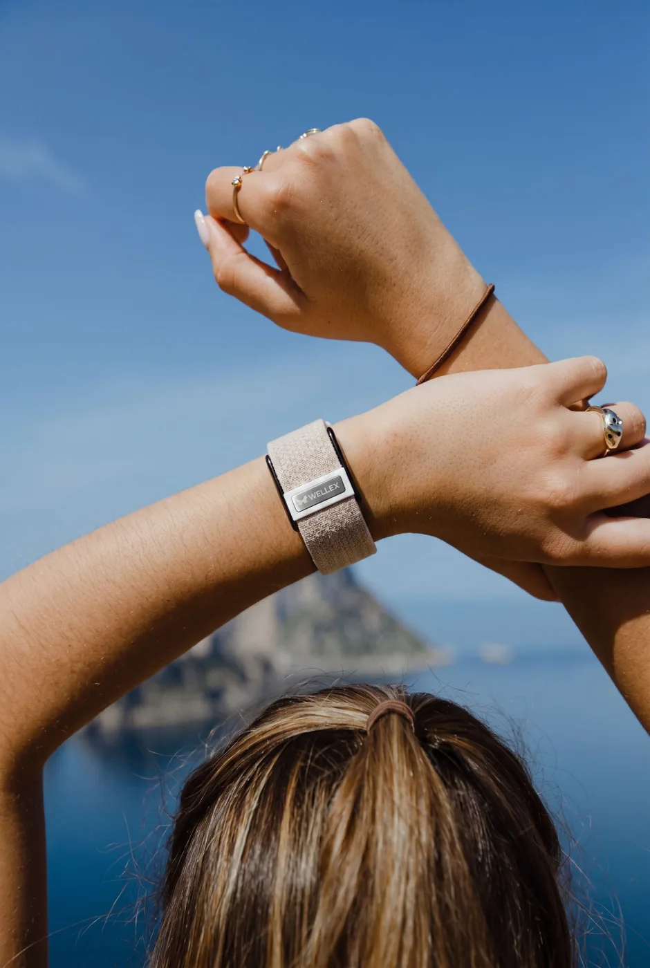 A wrist wearing the band, resting on a rail above open water