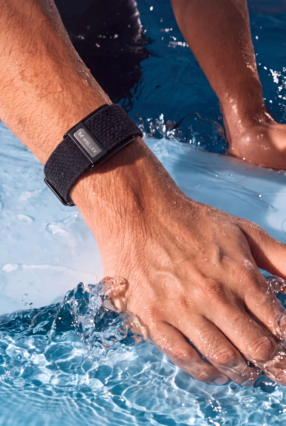 A hand wearing a Wellex band in water