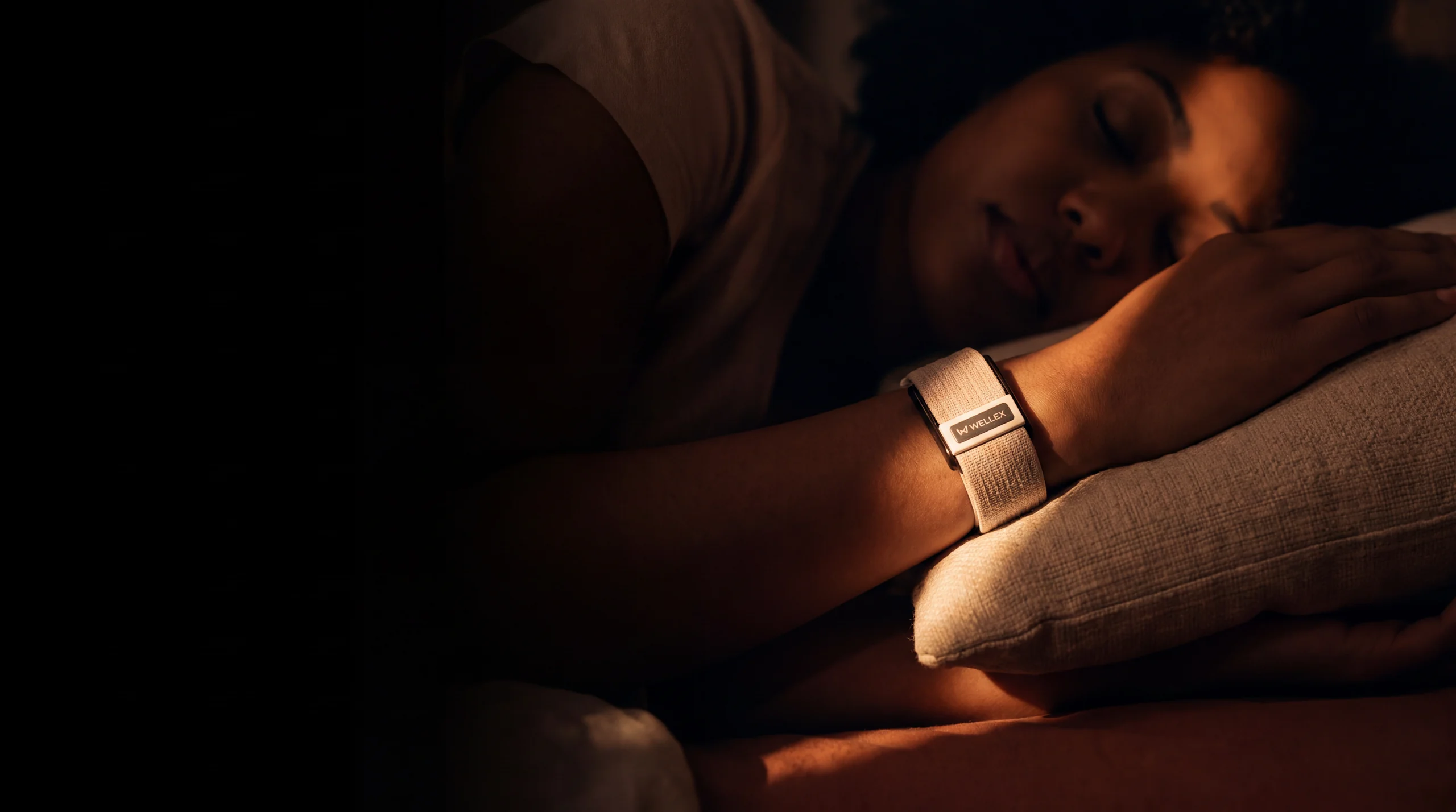 A person asleep at night wearing a Wellex band